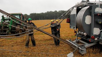 Drei Menschen und eine mobile Kabelzugwinde auf offenem Feld